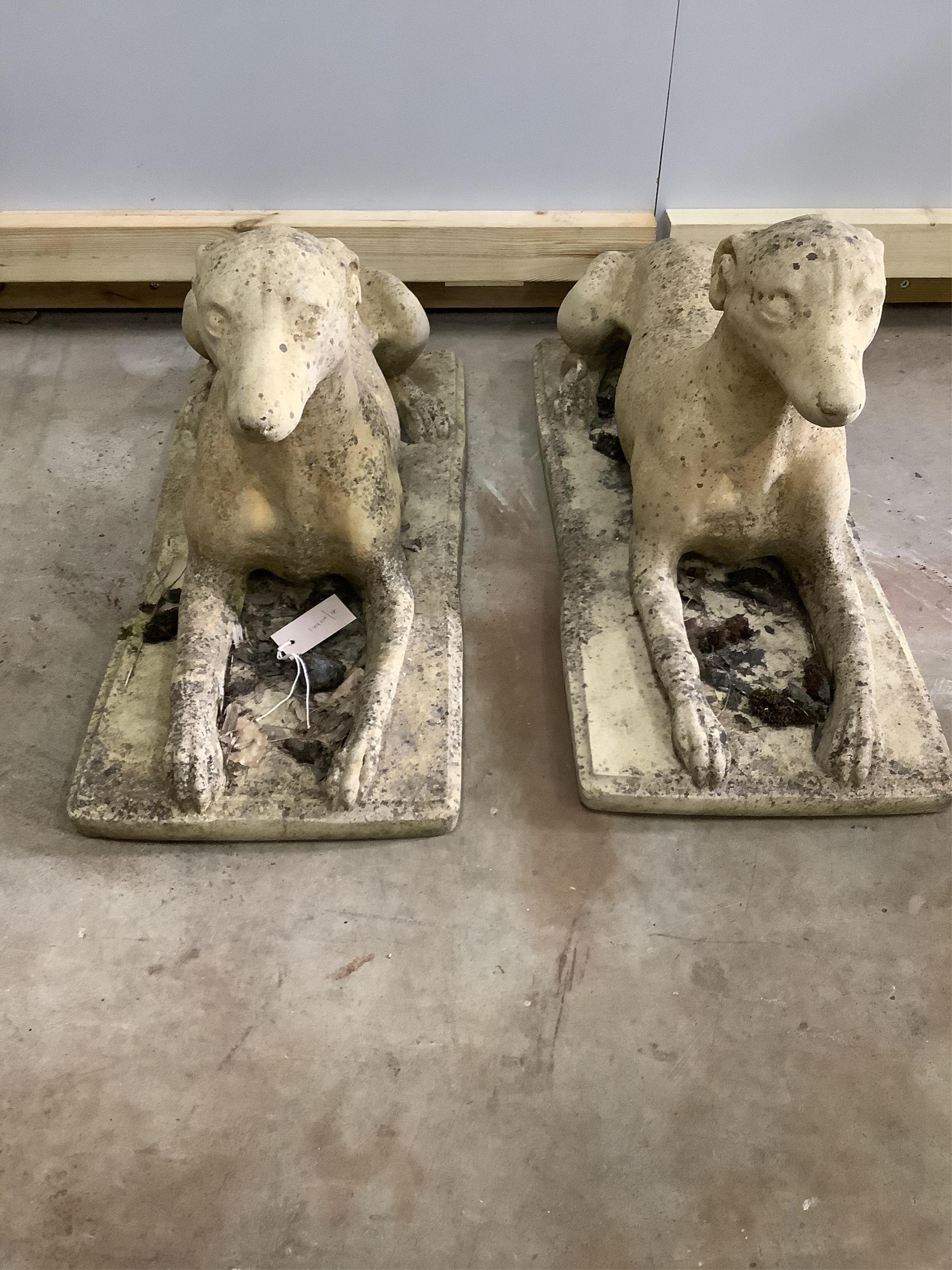 A pair of stone recumbent hound garden ornaments, length 70cm, width 30cm, height 34cm